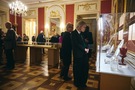 Goście oglądający dary wyeksponowane w gablotach w Sali Rady
